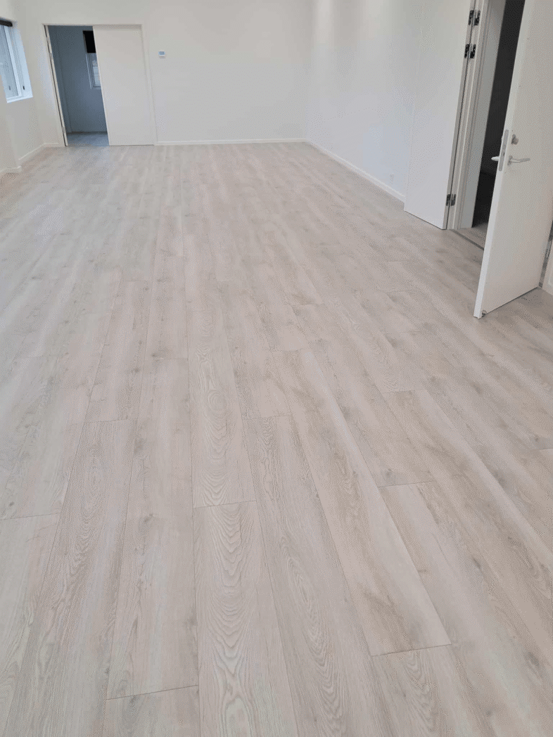 Moderne trægulv i lyst værelse med åbne døre.